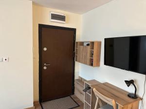 a room with a door and a desk and a television at Green Park Apartment - Brand New Studio! in Ruse