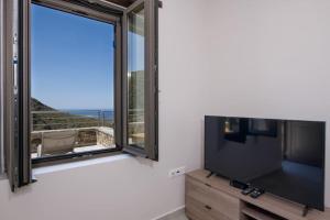 ein Wohnzimmer mit einem großen Fenster und einem Flachbild-TV in der Unterkunft Vigla Apartments No.3 in AmigdhalokeFálion