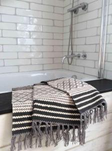 a bath tub with a checkered towel on it at The Old Stores, Luxury beach side selfcatered holiday cottage above the beach in Porthleven +26 photos