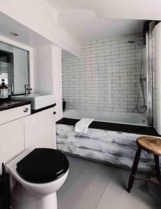 a bathroom with a tub and a toilet and a sink at The Old Stores, Luxury beach side selfcatered holiday cottage above the beach in Porthleven