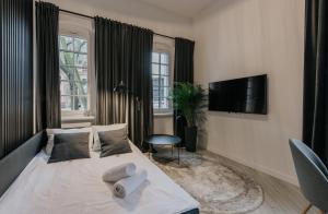 a bedroom with a white bed with a television and a rug at Stare Kasyno Aparthotel in Wrocław