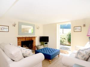 a living room with white furniture and a blue ottoman at Keepers Cottage in Petersfield