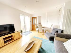 een woonkamer met een tv en een bank en een tafel bij White Eden, King bed, Free parking, Private patio, Fast WiFi, Dog, Family, Biker Friendly, Central Cornwall in St Austell