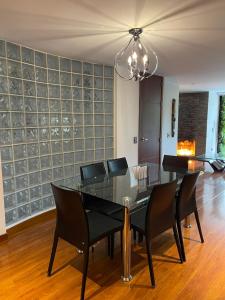 uma sala de jantar com uma mesa de vidro e cadeiras pretas em Lujoso Apartamento parque el Virrey em Bogotá
