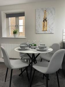 una mesa blanca con sillas y una botella de vino en la pared en Cedar House - 2 bedroom house with free parking by ShortStays4U en Kings Lynn