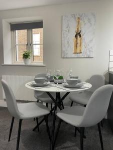 a white table with chairs and a wine bottle on the wall at Cedar House by ShortStays4U A modern 2 bedroom house with free parking in town centre! in King's Lynn