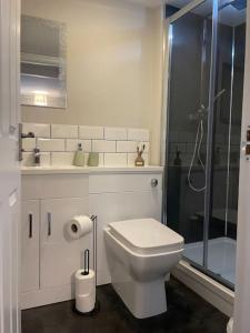 La salle de bains blanche est pourvue d'une douche et de toilettes. dans l'établissement Cedar House - 2 bedroom house with free parking by ShortStays4U, à King's Lynn