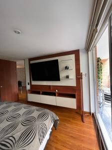 um quarto com uma cama e uma televisão de ecrã plano em Lujoso Apartamento parque el Virrey em Bogotá