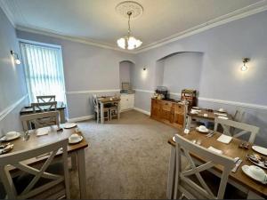 a dining room with tables and chairs and a kitchen at Sunny Bank Guest House in Tenby