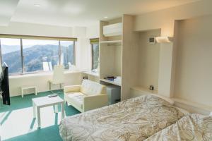熱海市にあるAtami-view Resortのベッドと椅子付きのホテルルーム