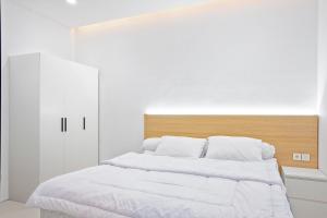 1 cama con sábanas blancas y cabecero de madera en Urbanisia, en Betek