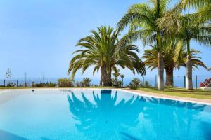 una piscina azul con palmeras en el fondo en Villa Pueblo Don Thomas, en San Sebastián de la Gomera