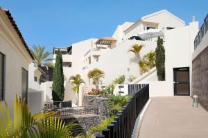 a white building with palm trees and a sidewalk at Villa Pueblo Don Thomas in San Sebastián de la Gomera
