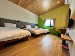 twee bedden in een kamer met groene muren en houten vloeren bij 池藍麗野民宿 in Chishang