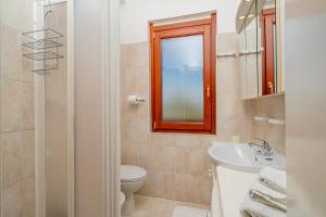 a bathroom with a toilet and a sink and a mirror at Casa Rosella by Wonderful Italy in Olbia