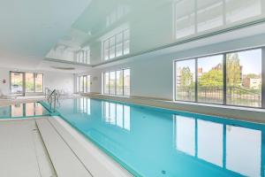 a swimming pool with blue water in a building with windows at Apartinfo Apartments Waterlane Island SPA in Gdańsk