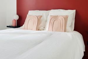 1 cama blanca con almohadas blancas y pared roja en Cosy 39m with terrace in Aubervilliers, en Aubervilliers