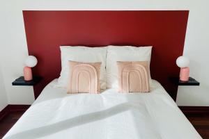 Una cama blanca con dos almohadas rosas. en Cosy 39m with terrace in Aubervilliers, en Aubervilliers