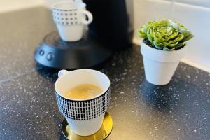 deux tasses de café et une plante en pot sur un comptoir dans l'établissement Cosy 39m with terrace in Aubervilliers, à Aubervilliers