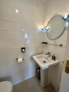 een badkamer met een wastafel, een spiegel en een toilet bij Sunny Bank Guest House in Tenby