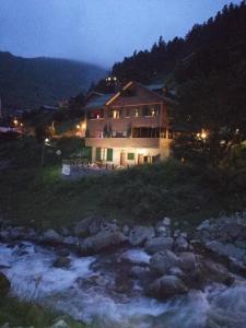 a house on a hill next to a river at night at Dagevi Butik Apart in Uzungöl