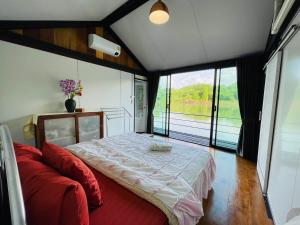 a bedroom with a bed and a red couch at เรือนแพคุณมน-Khun Mon Raft in Kanchanaburi