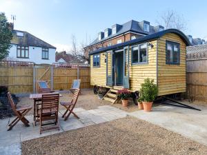 a small yellow tiny house with a table and chairs at Pass the Keys Whitstable Shepherds Hut minutes from the Harbour in Whitstable