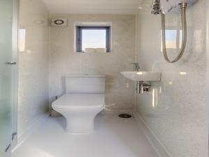 a white bathroom with a toilet and a sink at Pass the Keys Whitstable Shepherds Hut minutes from the Harbour in Whitstable