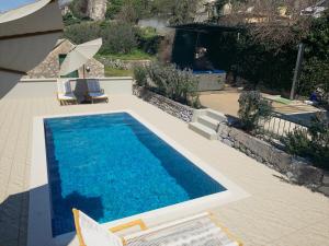 uma piscina com duas cadeiras e uma mesa em Holiday Home Aria em Podgora