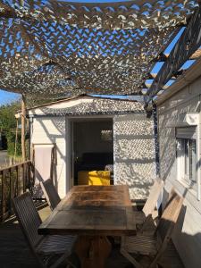 a wooden table and chairs on a patio at Chalet 47m2 dans PRL linge fourni in Gujan-Mestras