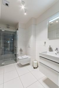 a white bathroom with a sink and a shower at Perfekt Apartments 5 Mórz Sianożęty in Sianozety