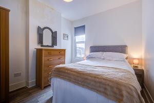 a bedroom with a bed and a dresser and a window at Pass the Keys City beach flat next to the sea sleeps up to 6 in Southend-on-Sea