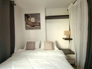 un letto bianco con due cuscini in una camera da letto di Studio Cozy @Sukumvit50 5mins to Bts Onnut a Bangkok