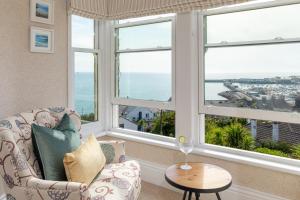 uma sala de estar com janelas, uma cadeira e uma mesa em Hotel Penzance em Penzance