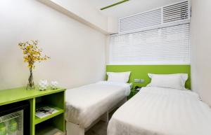 two beds in a room with green and white at Pop E INN-B&B in Hong Kong