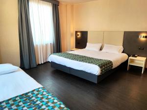 a hotel room with two beds and a window at Hotel Restaurant Forum in Beausoleil