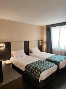 um quarto de hotel com duas camas e uma janela em Hotel Restaurant Forum em Beausoleil