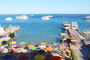 a beach with umbrellas and boats in the water at Shellghada Blue Beach in Hurghada