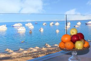 a bowl of fruit on a table with boats in the water at Shellghada Blue Beach in Hurghada