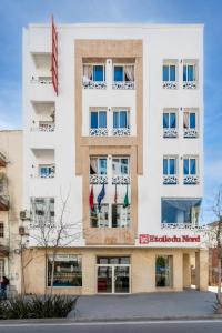 a white building with flags in the windows at Hotel Etoile Du Nord in Tangier