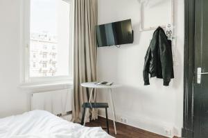 a bedroom with a table and a tv on the wall at Pyjama Park St. Pauli in Hamburg