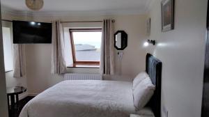 a bedroom with a white bed and a window at Lahiff's Bay View Guest House in Spanish Point