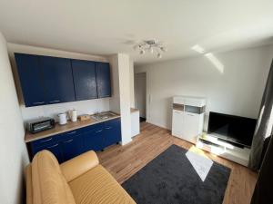ein Wohnzimmer mit einem Sofa und eine Küche mit blauen Schränken in der Unterkunft Klytti‘s Pension in Sendenhorst