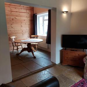 uma sala de estar com uma mesa e uma televisão em Spacious self catering accommodation near HayOnWye em Hay-on-Wye
