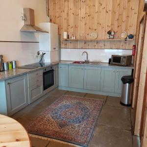una cucina con armadi blu e un tappeto sul pavimento di Spacious self catering accommodation near HayOnWye a Hay-on-Wye