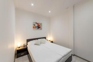 1 dormitorio con 1 cama blanca grande y 2 lámparas en E-home Apartments en Varna