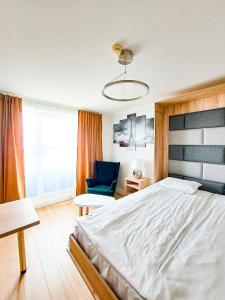 a bedroom with a large bed and a blue chair at Hotel Sympozjum & SPA in Kraków