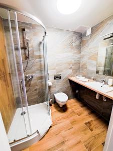 a bathroom with a shower and a toilet and a sink at Hotel Sympozjum & SPA in Kraków