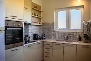 uma cozinha com armários brancos e uma janela em Kotrona Farmhouse - Argassi Zakynthos em Argasi
