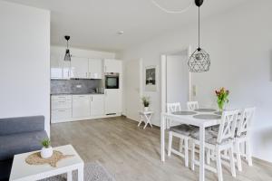ein weißes Wohnzimmer mit einem Tisch und Stühlen in der Unterkunft Ferienwohnung Hafeneck Moba-Travel in Lübeck